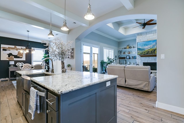 kitchen featuring pendant lighting, dishwasher, a kitchen island with sink, and light hardwood / wood-style flooring