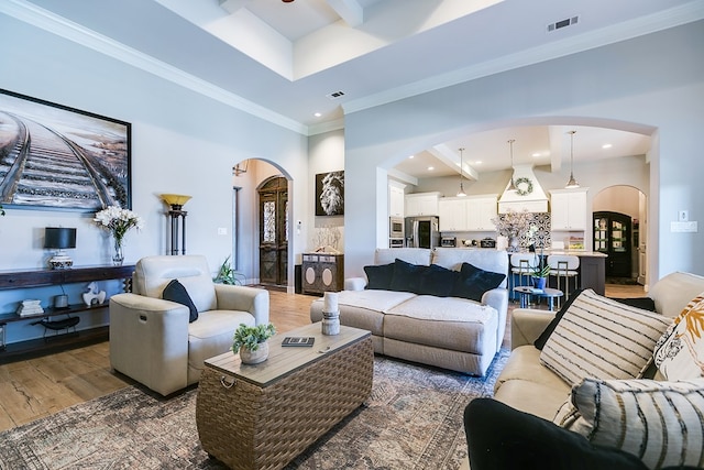 living room with crown molding, dark wood-type flooring, beamed ceiling, and a high ceiling