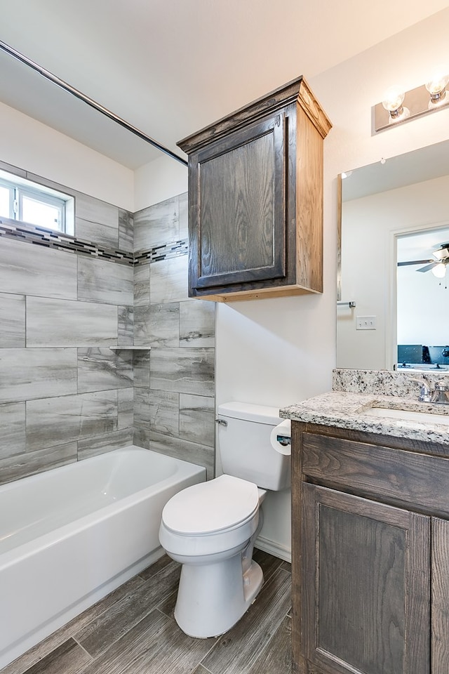 full bathroom featuring wood tiled floor, toilet, bathing tub / shower combination, vanity, and a ceiling fan