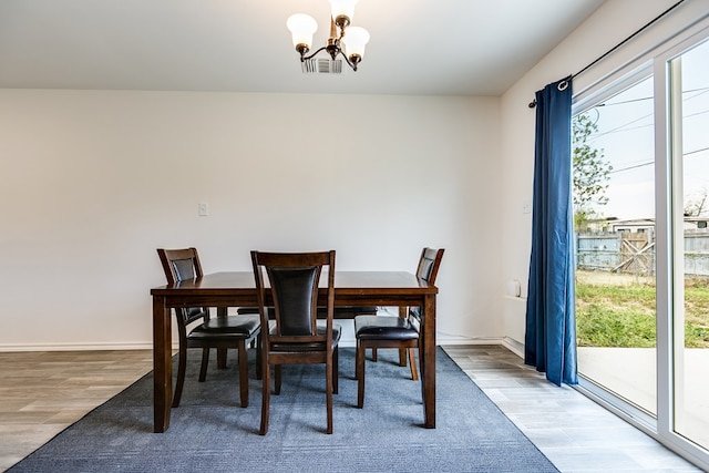 dining room with a notable chandelier, visible vents, baseboards, and wood finished floors