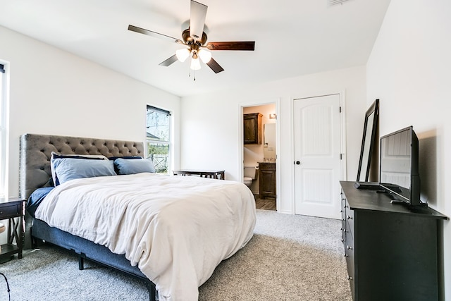 bedroom with light colored carpet, ceiling fan, and ensuite bathroom