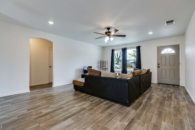 living room with visible vents, a ceiling fan, wood finished floors, arched walkways, and baseboards