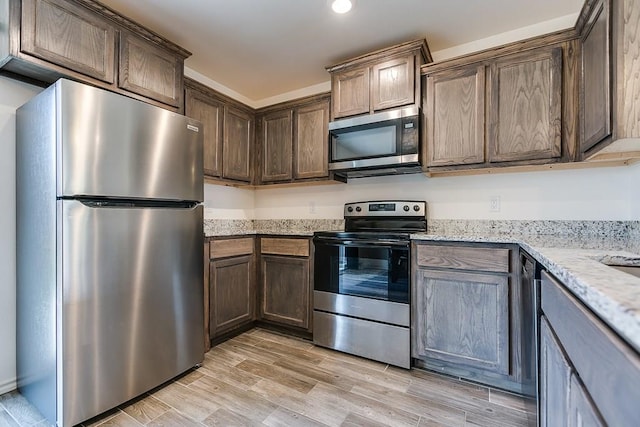 kitchen featuring light wood-style flooring, recessed lighting, appliances with stainless steel finishes, light stone countertops, and dark brown cabinets