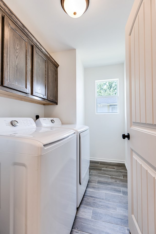 laundry room featuring washer and clothes dryer, cabinet space, baseboards, and wood tiled floor