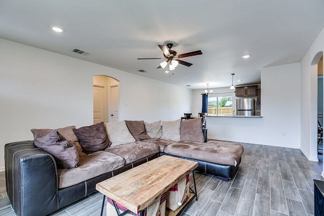 living room featuring arched walkways, visible vents, and wood finished floors