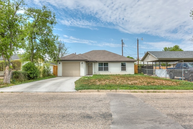 ranch-style home featuring an attached garage, fence, driveway, and roof with shingles