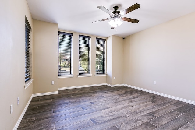 spare room featuring dark wood-style floors, a ceiling fan, and baseboards