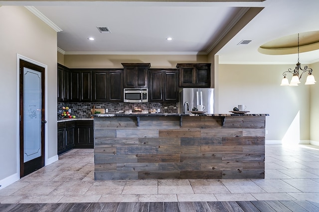 kitchen featuring visible vents, appliances with stainless steel finishes, an island with sink, and decorative backsplash