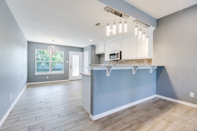 kitchen featuring white cabinetry, pendant lighting, a kitchen breakfast bar, and kitchen peninsula