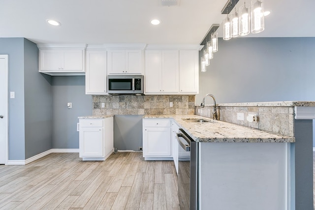 kitchen with sink, white cabinetry, decorative light fixtures, appliances with stainless steel finishes, and light stone countertops