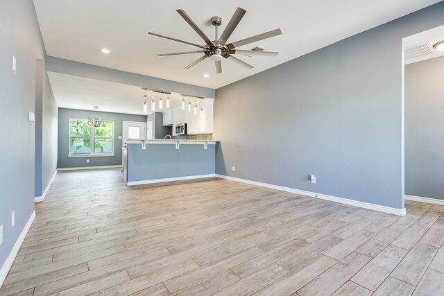 unfurnished living room featuring ceiling fan, track lighting, and light wood-type flooring