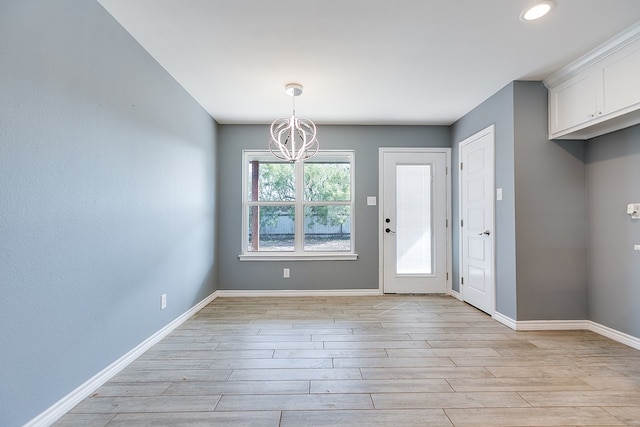 unfurnished dining area with a notable chandelier and light wood-type flooring