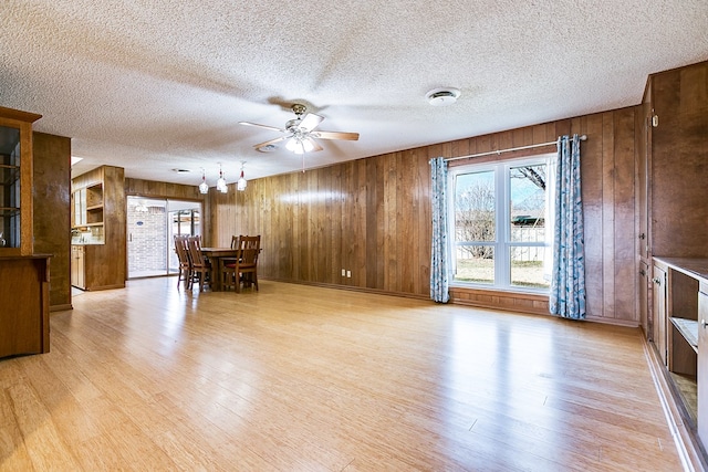 living room featuring wooden walls, light hardwood / wood-style floors, and ceiling fan