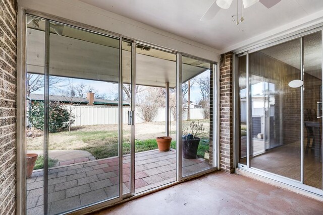 doorway to outside featuring brick wall, a wealth of natural light, and ceiling fan