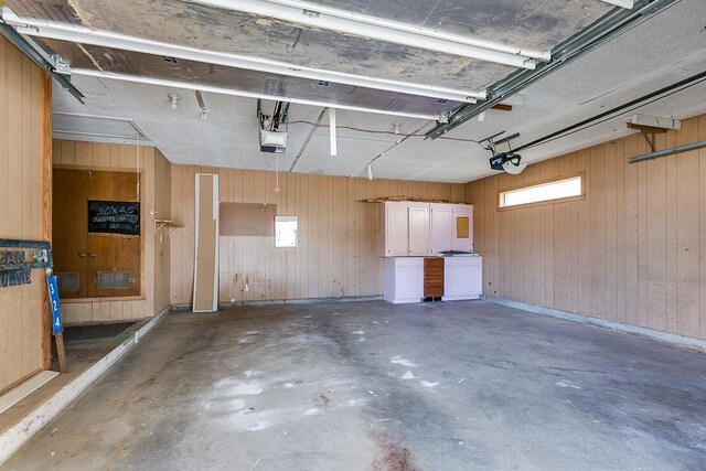 garage with a garage door opener and wood walls