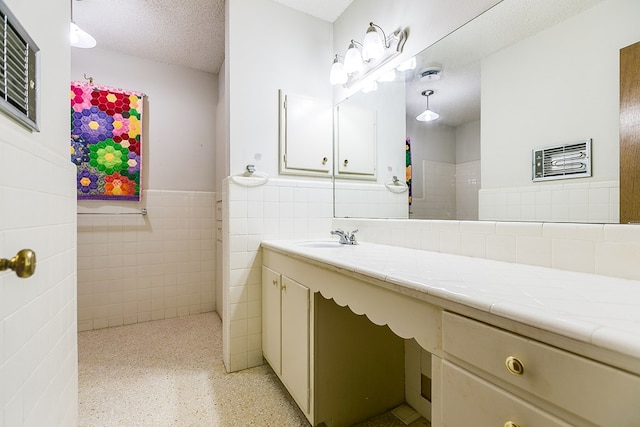 bathroom with tile walls, vanity, and a textured ceiling