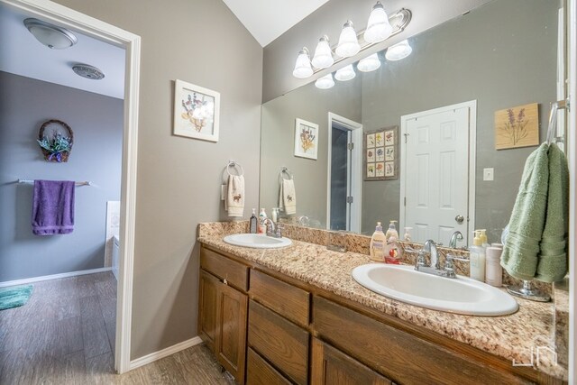 full bathroom featuring baseboards, double vanity, a sink, and wood finished floors