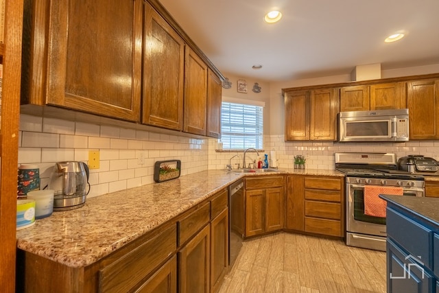 kitchen with a sink, brown cabinets, light wood-type flooring, stainless steel appliances, and decorative backsplash