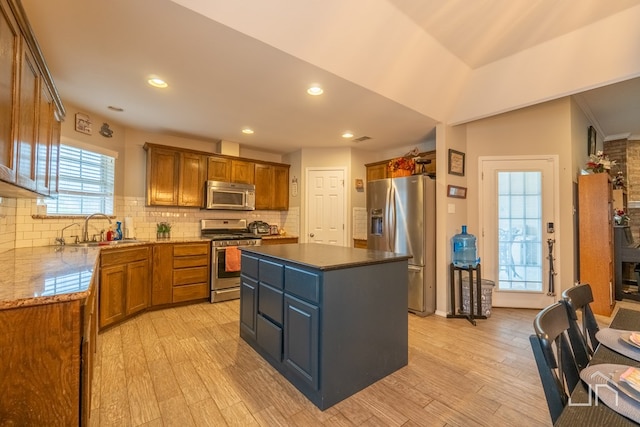 kitchen featuring a center island, brown cabinetry, light wood-style floors, and stainless steel appliances
