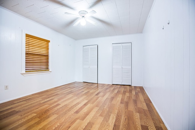 2609 W Harris Ave, San Angelo, TX 76901 - unfurnished bedroom featuring two closets, light wood-type flooring, and ceiling fan