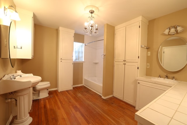 full bathroom with shower / bathtub combination, sink, hardwood / wood-style flooring, toilet, and an inviting chandelier