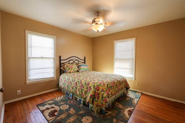 bedroom featuring ceiling fan, hardwood / wood-style floors, and multiple windows