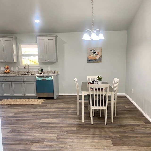 dining space featuring dark wood-style flooring, a notable chandelier, and baseboards