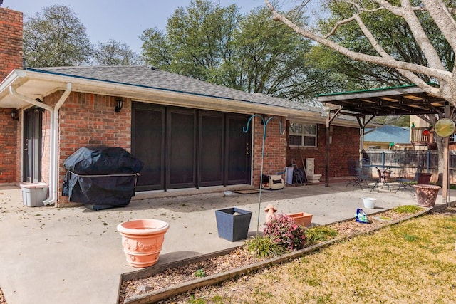 rear view of property with a patio, brick siding, fence, roof with shingles, and a chimney