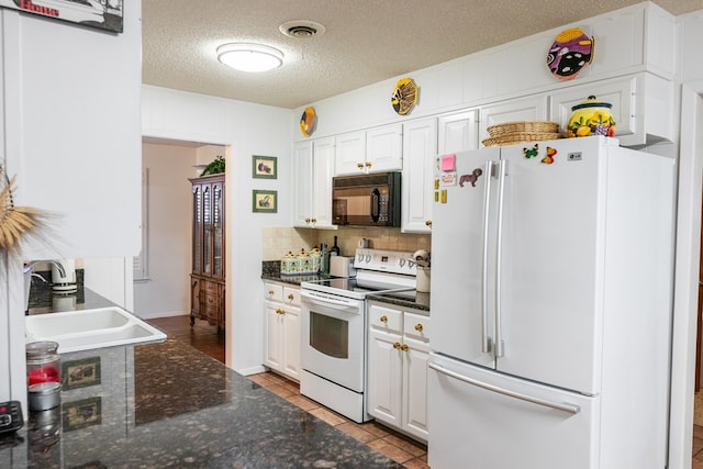 kitchen with white appliances, light tile patterned floors, visible vents, white cabinets, and a sink