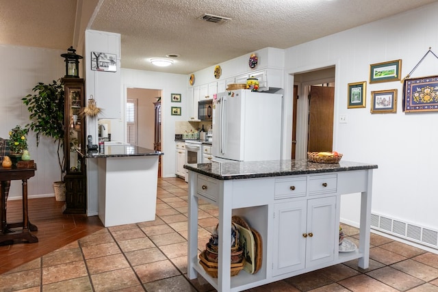 kitchen with white appliances, visible vents, and white cabinetry