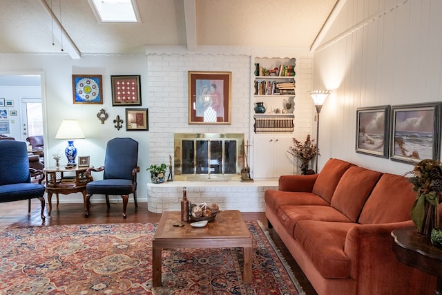 living room featuring a brick fireplace, vaulted ceiling with skylight, a textured ceiling, and wood finished floors