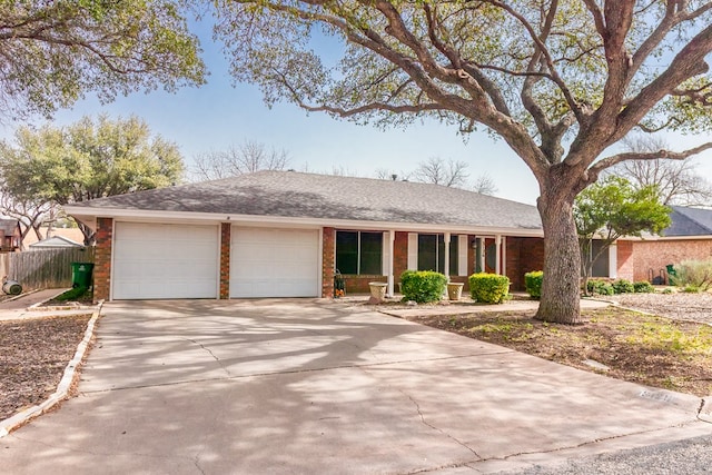 single story home featuring a garage, brick siding, fence, driveway, and roof with shingles