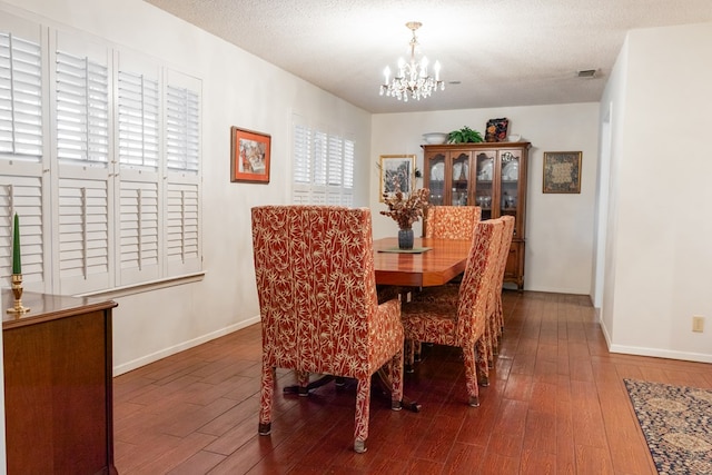 dining area with baseboards, visible vents, wood finished floors, an inviting chandelier, and a textured ceiling