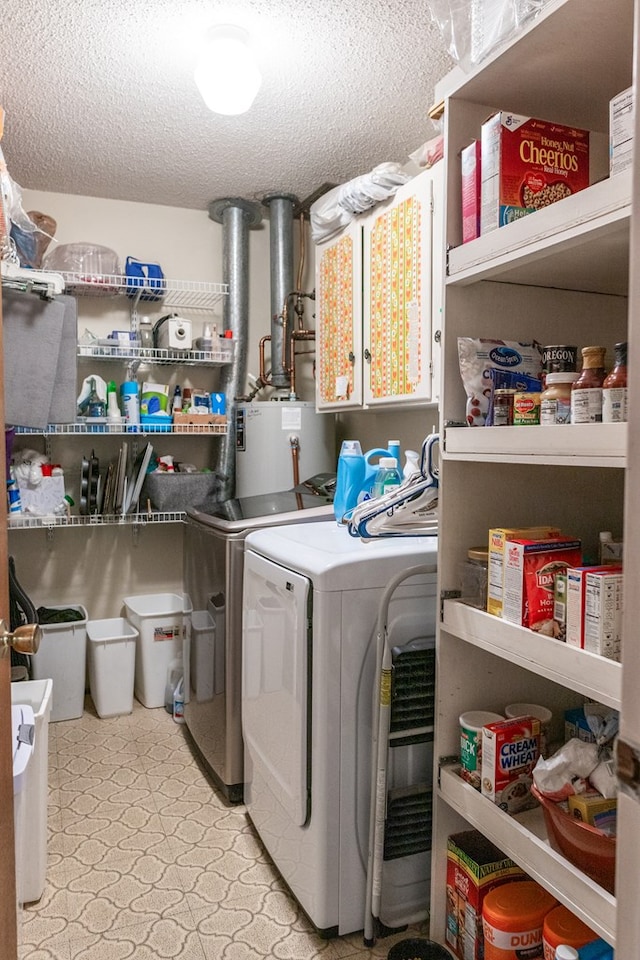 clothes washing area with washer and clothes dryer, light floors, cabinet space, water heater, and a textured ceiling