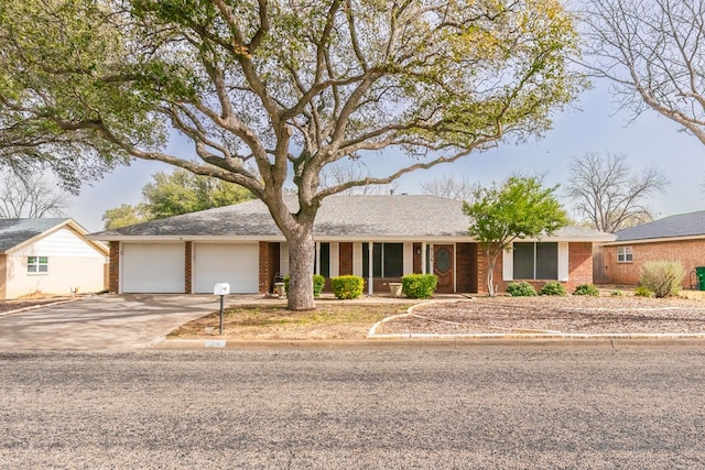 ranch-style house featuring driveway, an attached garage, and brick siding