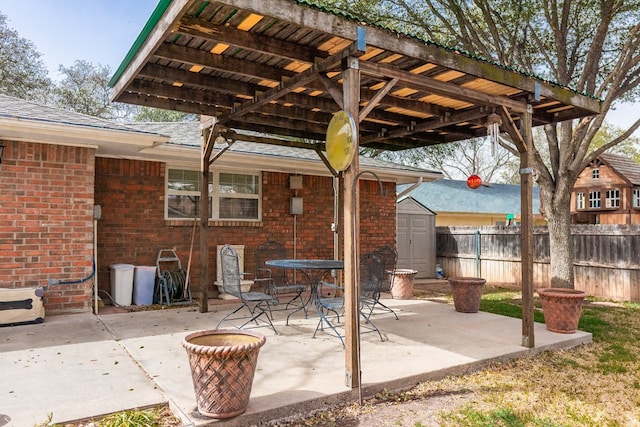 view of patio / terrace featuring an outbuilding, a storage unit, outdoor dining area, and fence