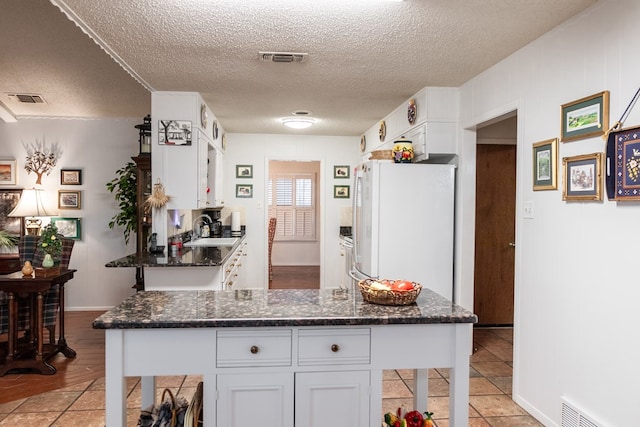 kitchen with white cabinetry, visible vents, a sink, and freestanding refrigerator