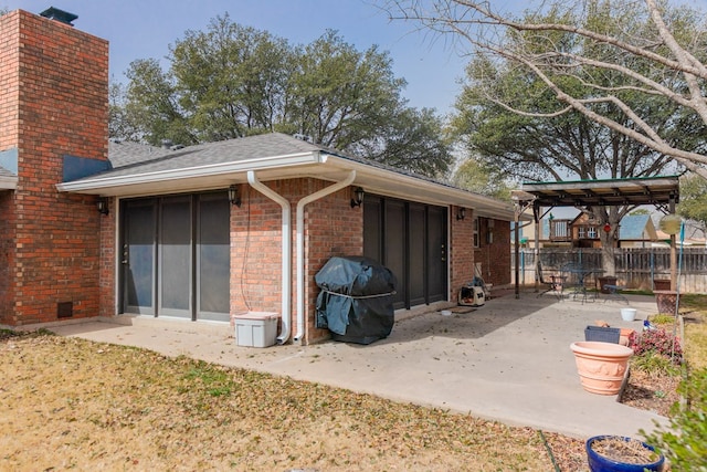 back of property featuring a shingled roof, a patio, a chimney, fence, and brick siding