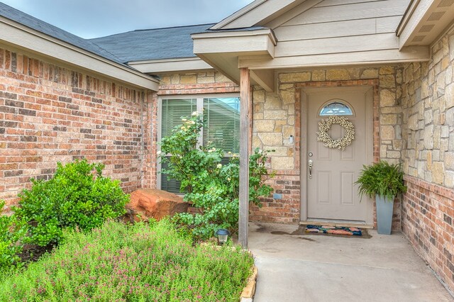 2873 Joshua St, San Angelo, TX 76905 - view of exterior entry with stone siding, brick siding, and a shingled roof