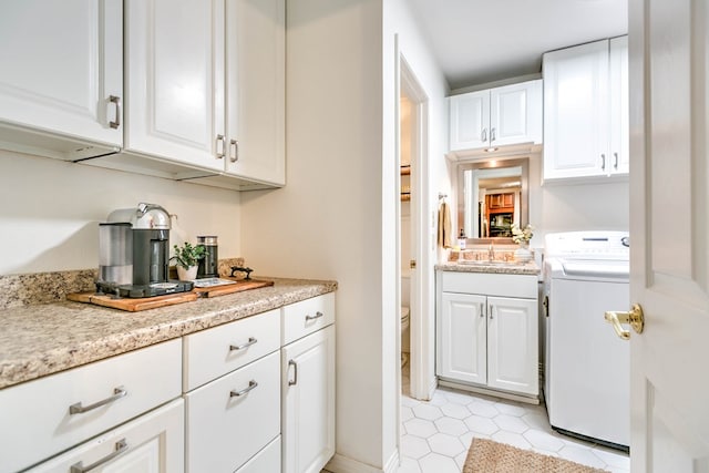 2805 Alta Vista Ln, San Angelo, TX 76904 - kitchen with washer / dryer, light countertops, white cabinetry, and light tile patterned flooring
