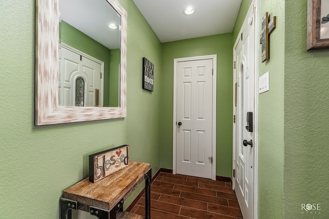 doorway to outside featuring baseboards, recessed lighting, wood finish floors, and a textured wall