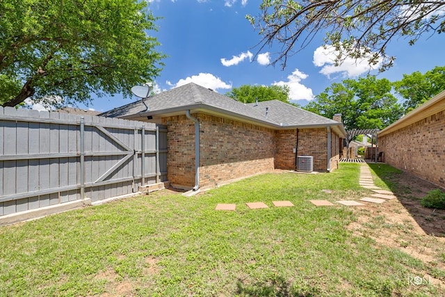 view of yard featuring a gate, fence, and central AC