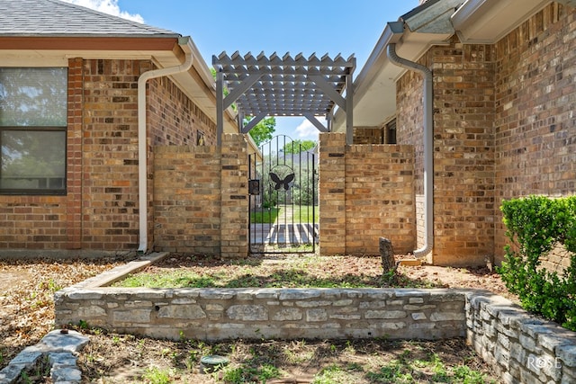 view of side of property with a pergola, brick siding, fence, and a gate