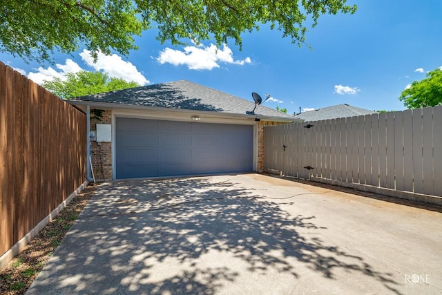 garage with a gate, concrete driveway, and fence