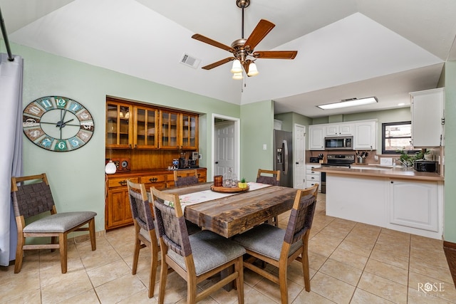 dining area with ceiling fan, visible vents, light tile patterned flooring, and vaulted ceiling