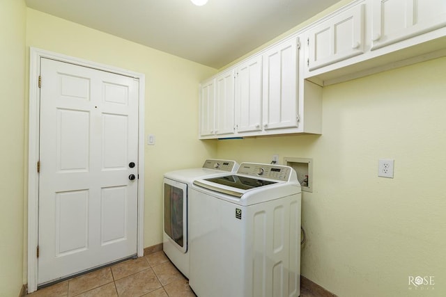 washroom featuring washing machine and dryer, light tile patterned flooring, cabinet space, and baseboards