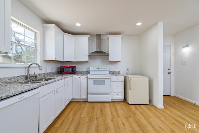 kitchen with white cabinetry, white appliances, wall chimney exhaust hood, and sink