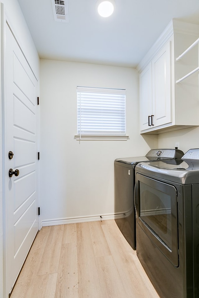 laundry room with cabinets, separate washer and dryer, and light wood-type flooring