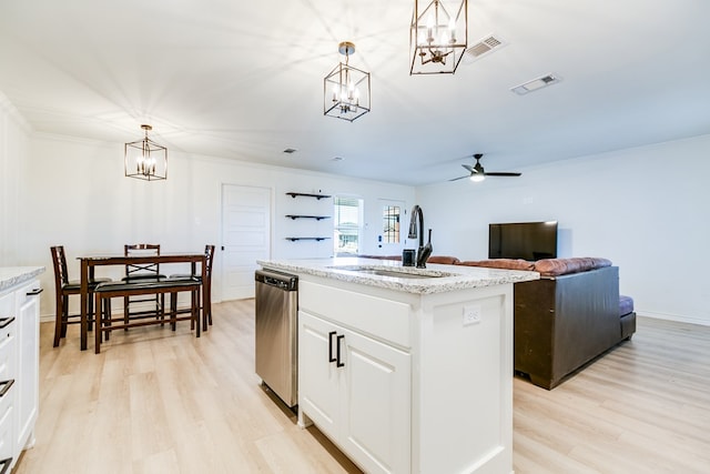 kitchen with a kitchen island with sink, sink, decorative light fixtures, and stainless steel dishwasher