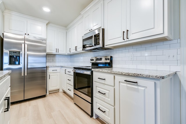 kitchen featuring stainless steel appliances, white cabinetry, and light stone counters